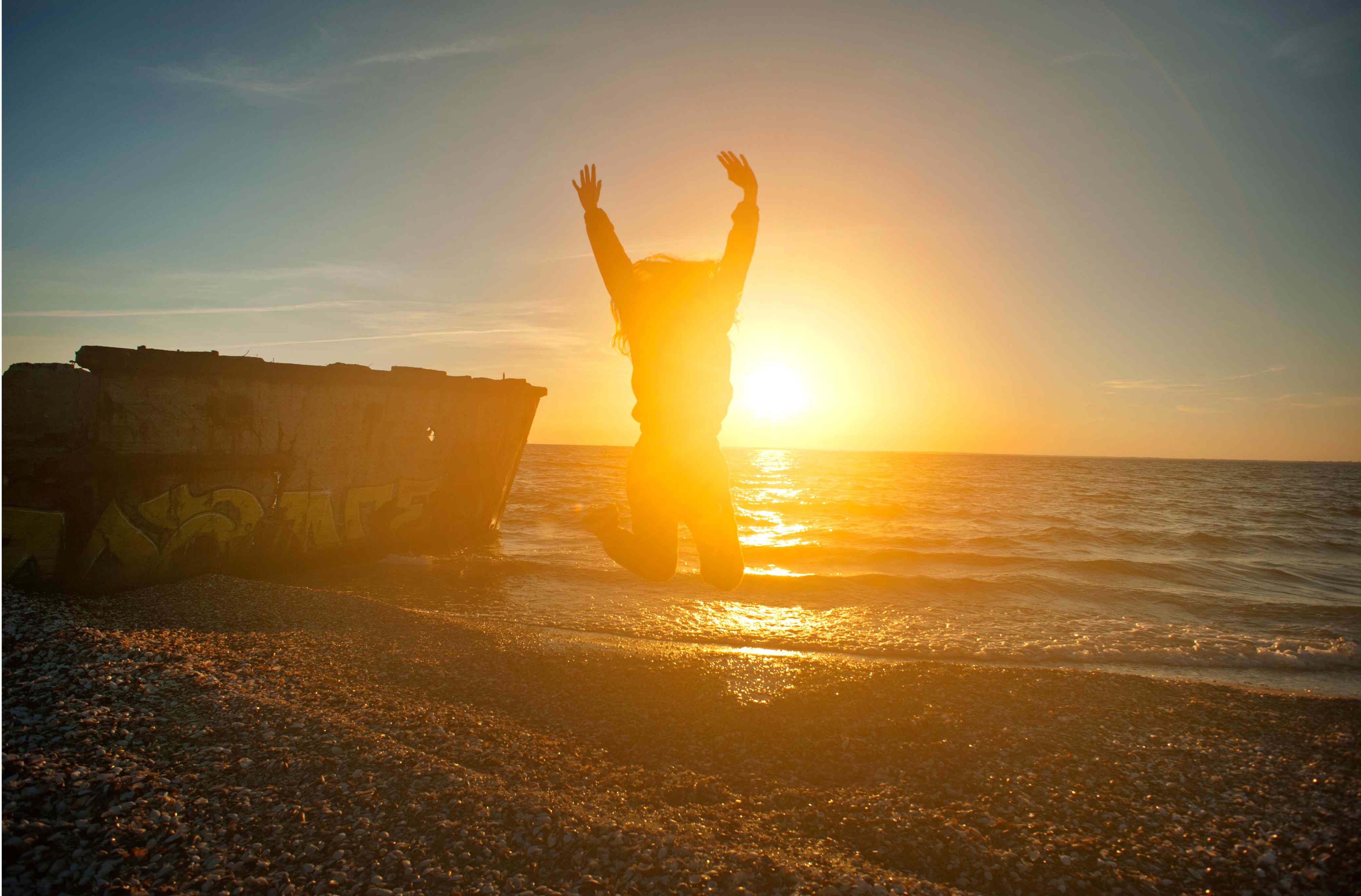 Person jumping with joy at sunset on the beach