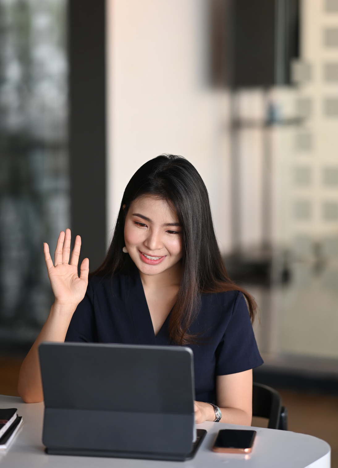 Professional woman in virtual coaching session, waving warmly at camera